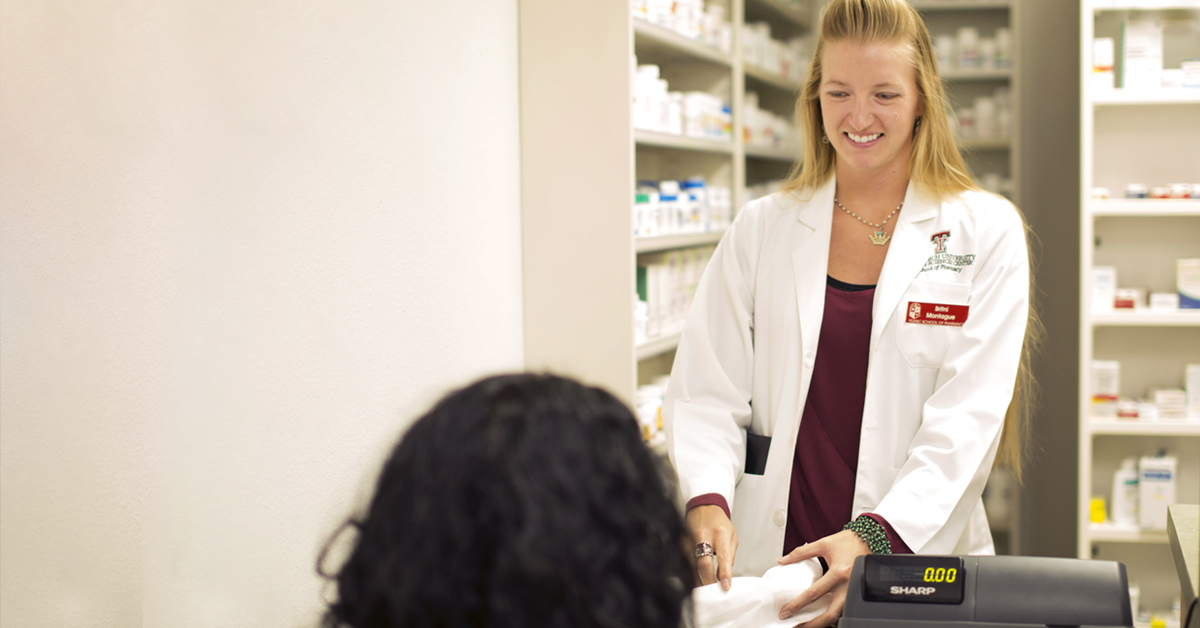 Pharamacy Student at the cash register, learn about the top five reasons for pursuing a pharmacy career.