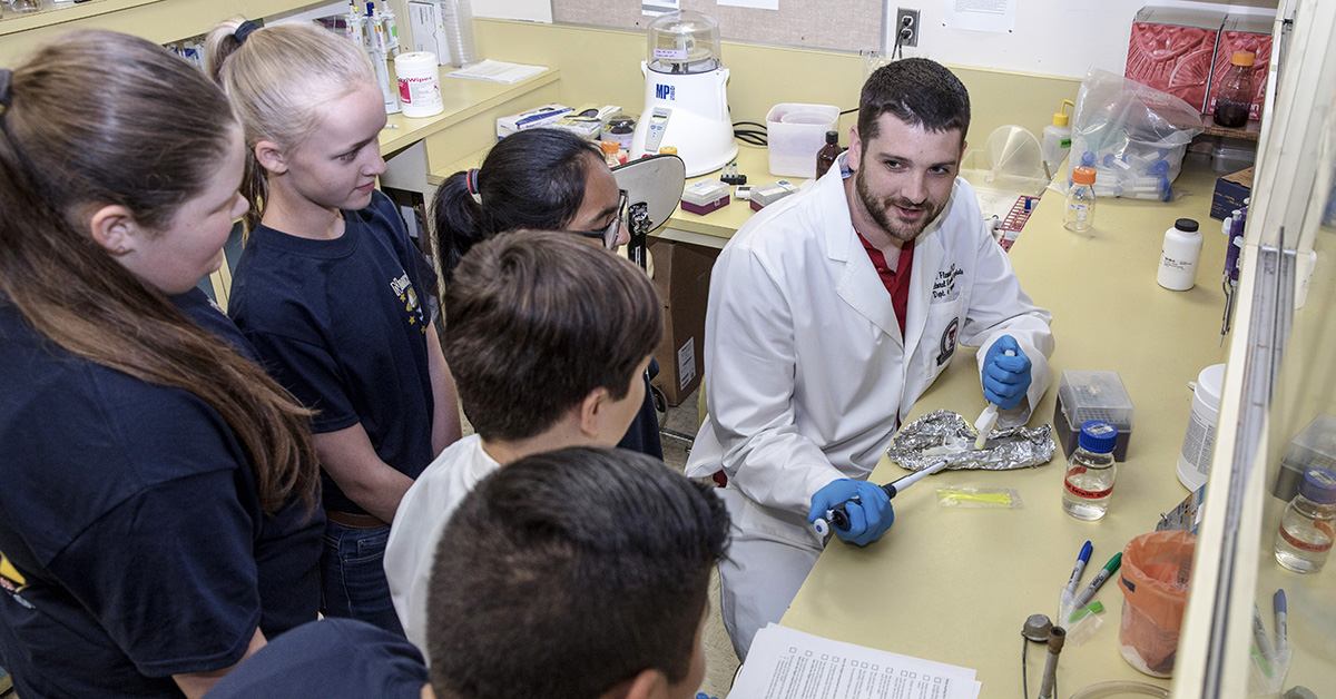 Derek Fleming, Ph.D., assists students with an experiment 