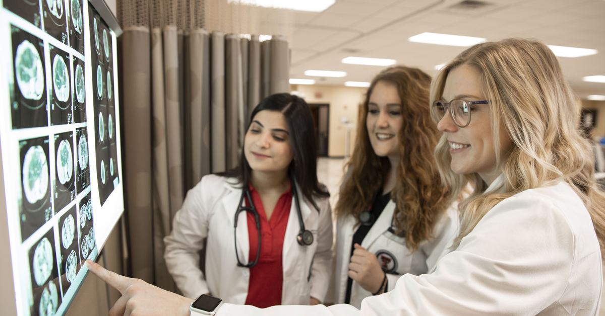 TTUHSC physician assistant students examining images on a medical lightbox.