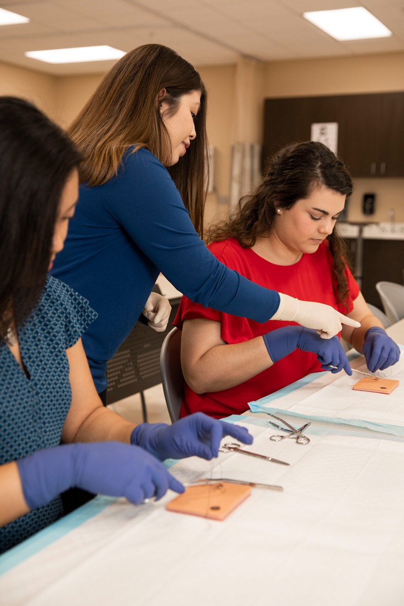 TTUHSC physician assistant students in a lab with faculty practicing sutures.