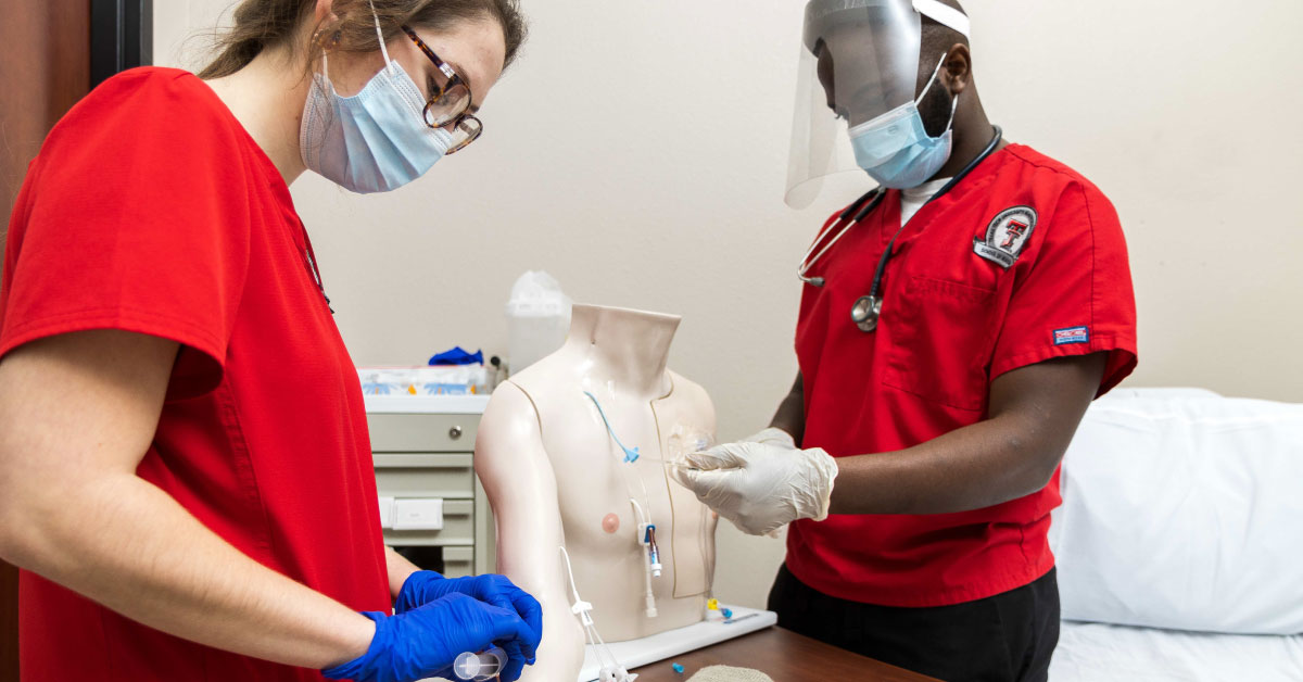 Nursing students wearing TTUHSC red scrubs and masks.
