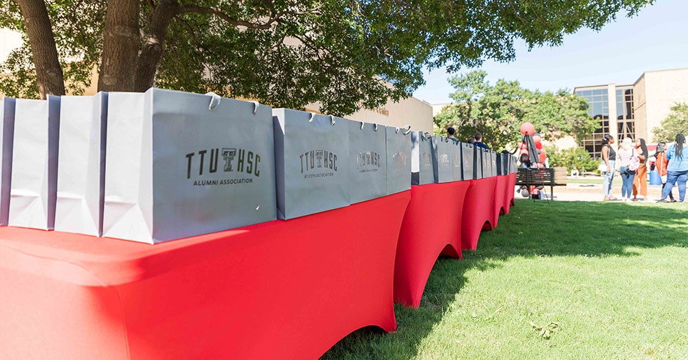 lined up bags with the TTUHSC logo, containing scrubs and stethoscopes