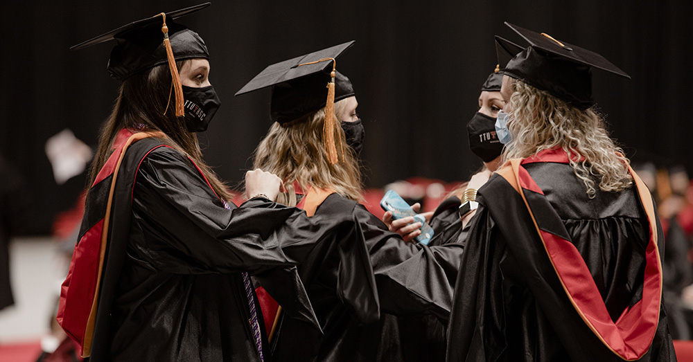 three school of nursing graduates talking in their graduation caps