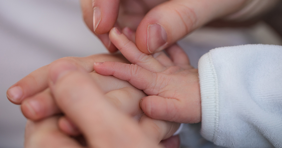 parent holding infant hand