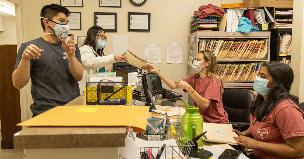 students who volunteer at the free clinic work in masks during the pandemic 
