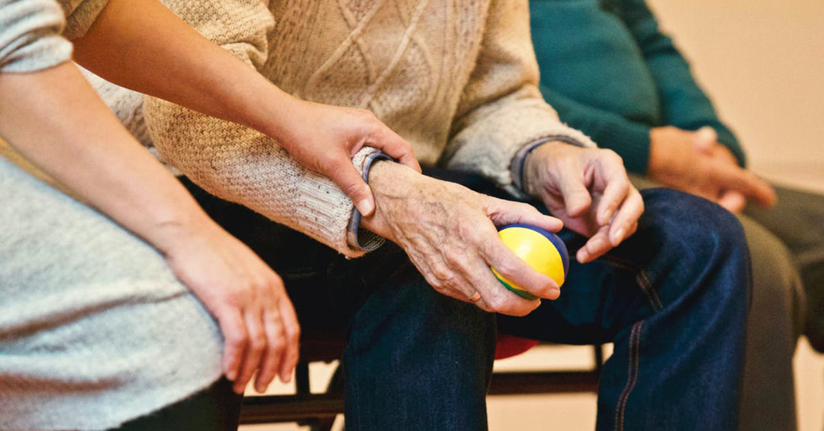hands touching elderly hands holding a ball in health care setting