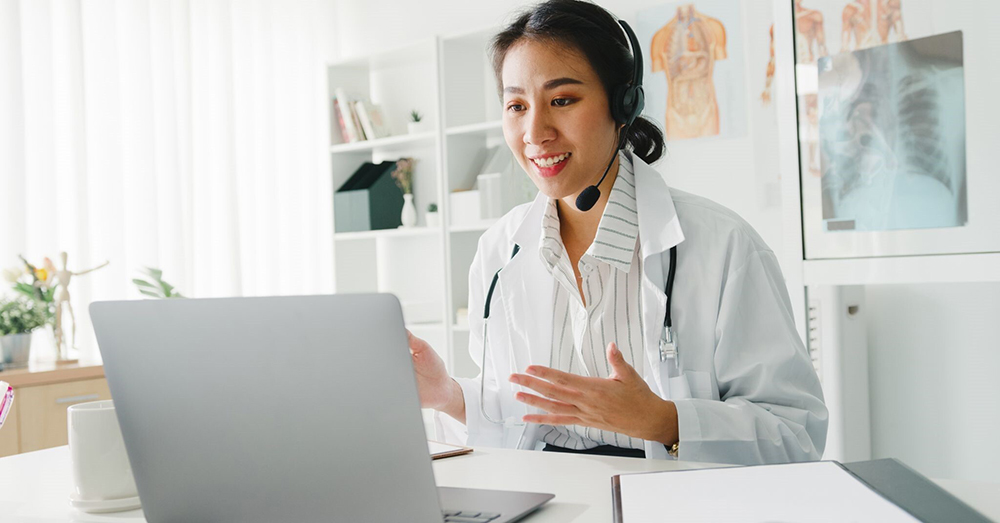 woman physician with headset and laptop perforning telehealth routine 