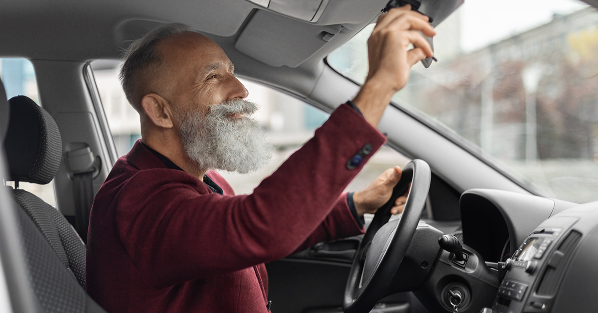 Older driver adjusting his rearview mirror