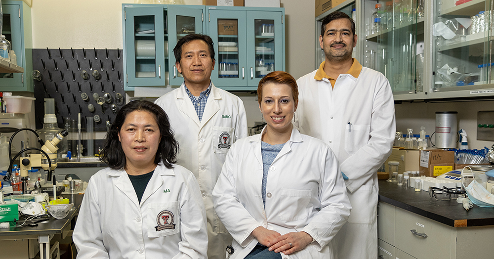 Liang, PhD, standing with his team