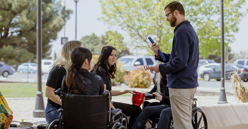 occupational therapist speaking with patients in wheelchairs outside 
