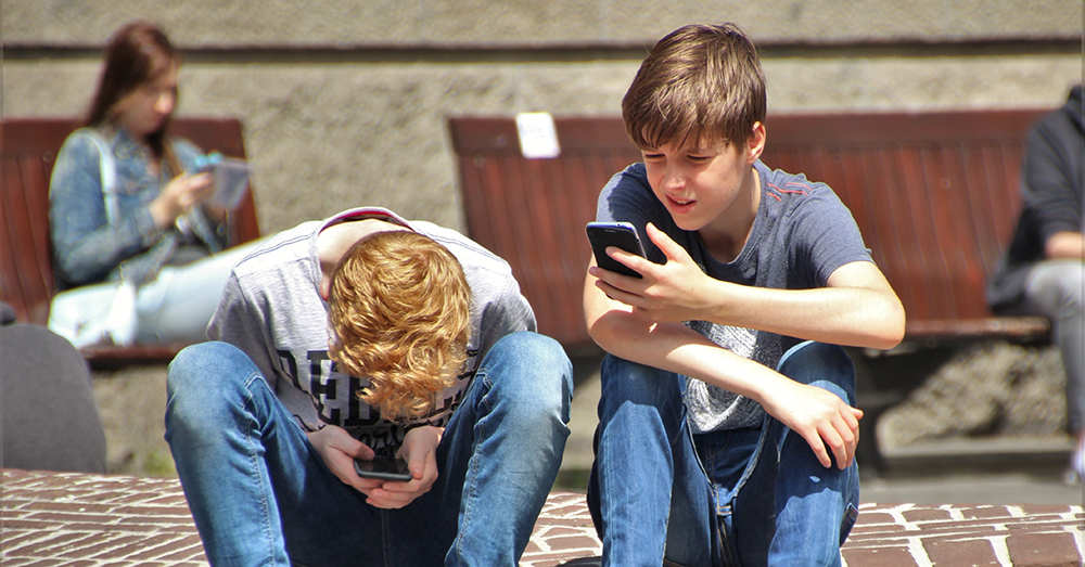 two adolescent boys on their phones
