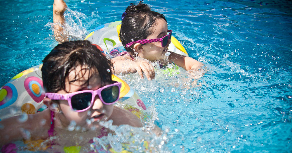kids swimming in a pool with floaties and sunglasses