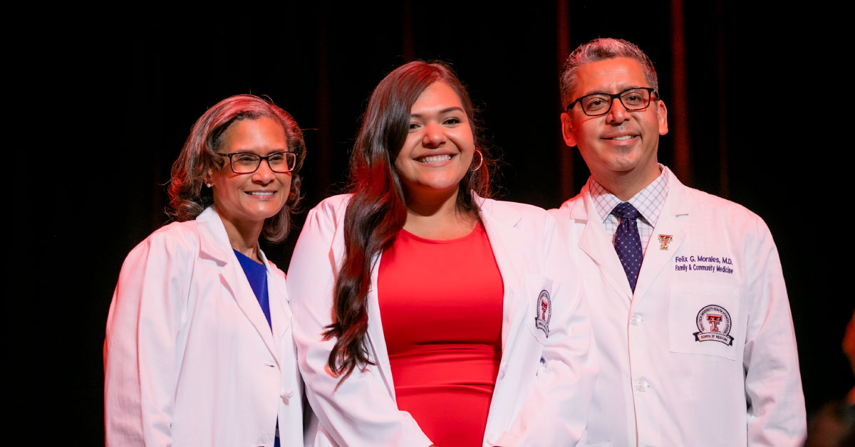 Female TTUHSC medical student receives her white coat on stage.