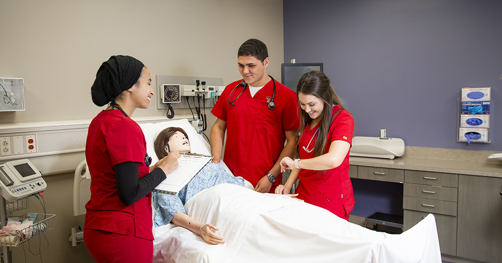 nursing students practicing their skills in red scrubs