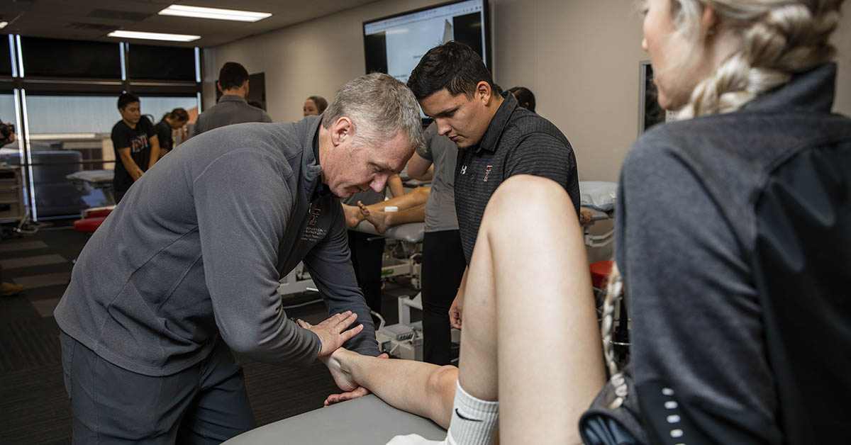athletic trainer looking at an athlete's leg