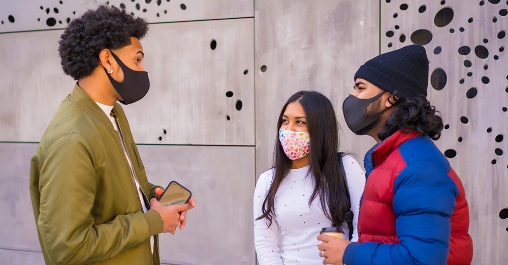 three people talking wearing face masks
