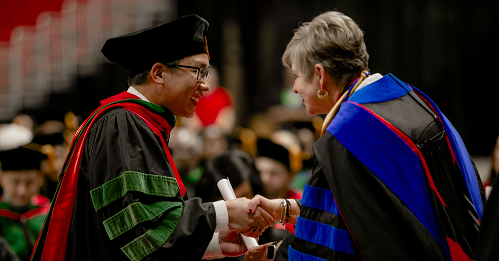graduate and Dr. Lori Rice-Spearman shaking hands