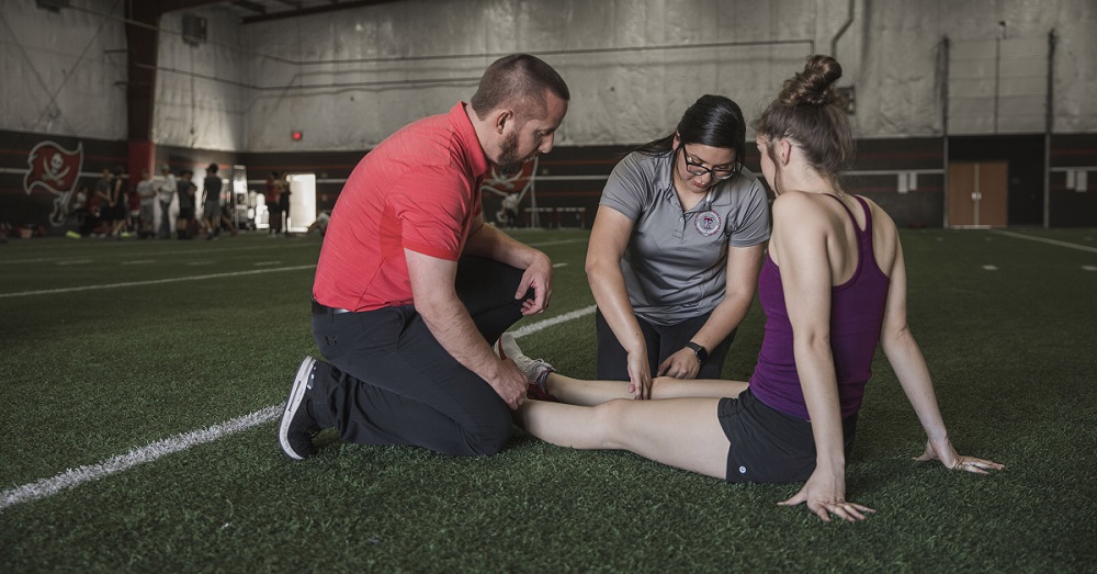 physical therapist and student athlete on a field