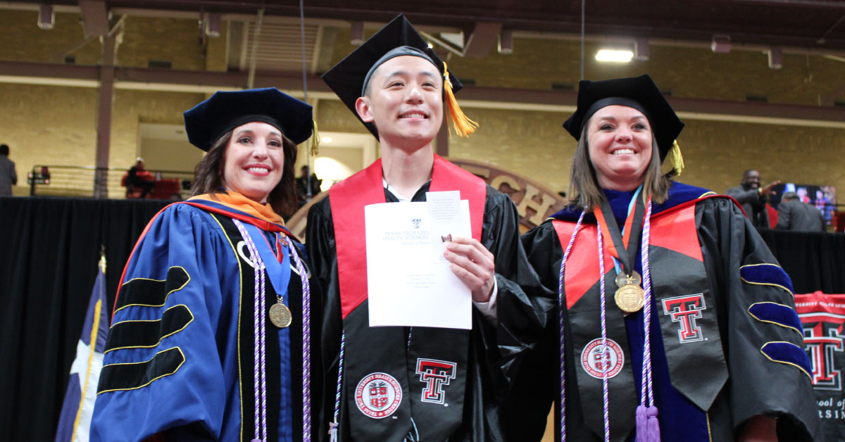 Male TTUHSC nursing student receives his degree and stands with two female faculty members at graduation.