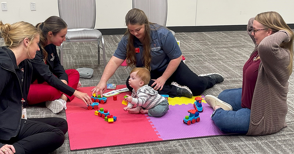 child playing on colorful mat with healthcare professionals