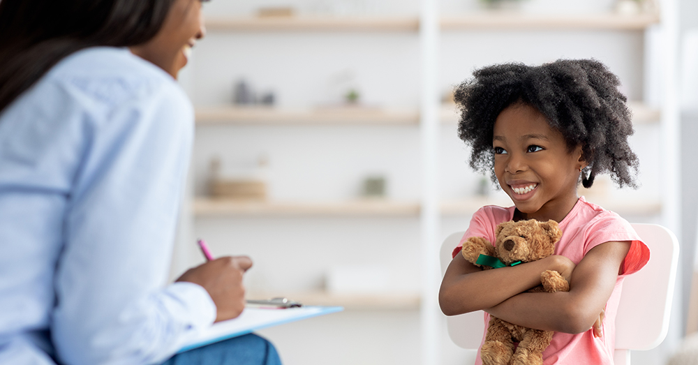 child with toy smiling at therapist