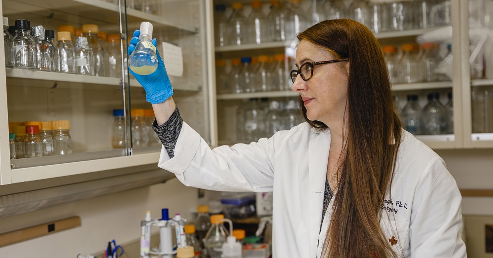Kendra Rumbaugh, Ph.D., holding a container in her lab