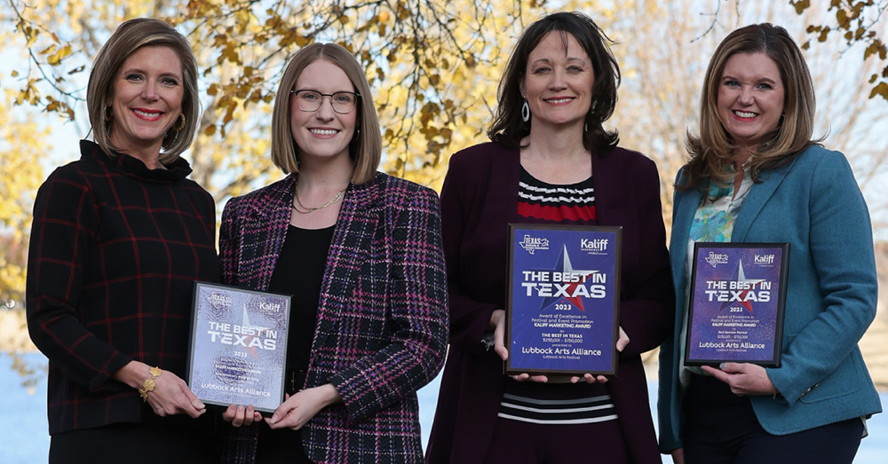 Four woman hold award plaques.
