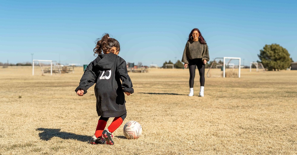 mother and daughter playing soccer on a field