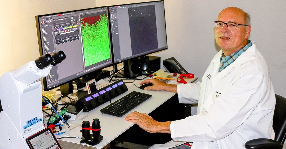 Ulrich Bickel, M.D. at a computer with a microscope on his desk