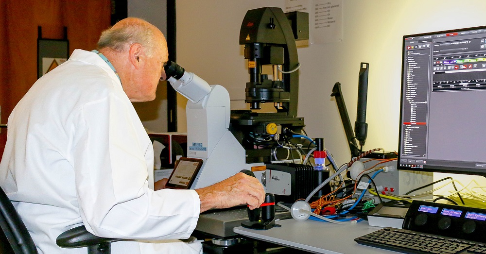 Ulrich Bickel, M.D., looking through a microscope