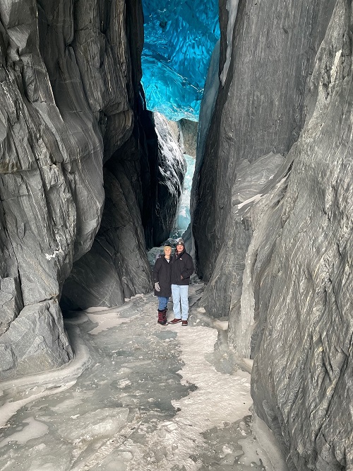 Two people standing in front of a glacier in Alaska 