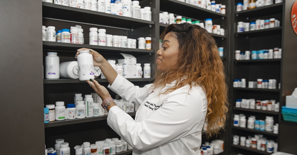pharmacist at TTUHSC with shelves of medication