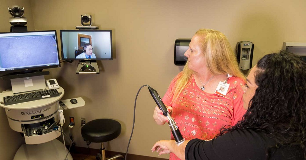 woman receiving medical test via telemedicine, with a doctor on the screen beside her. 