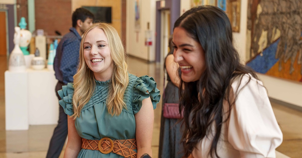 two women in the FMAT program laughing and talking during the 2023 celebration