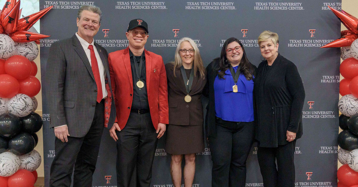 five people stand in front of TTUHSC step-and-repeat