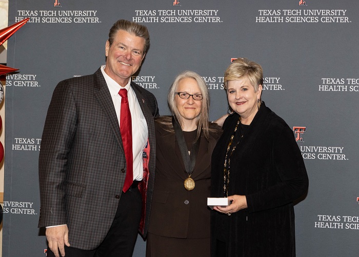  three people stand in front of a TTUHSC step and repeat