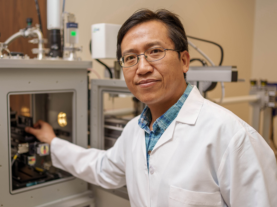 Male TTUHSC researcher wears a white coat and works in his lab.