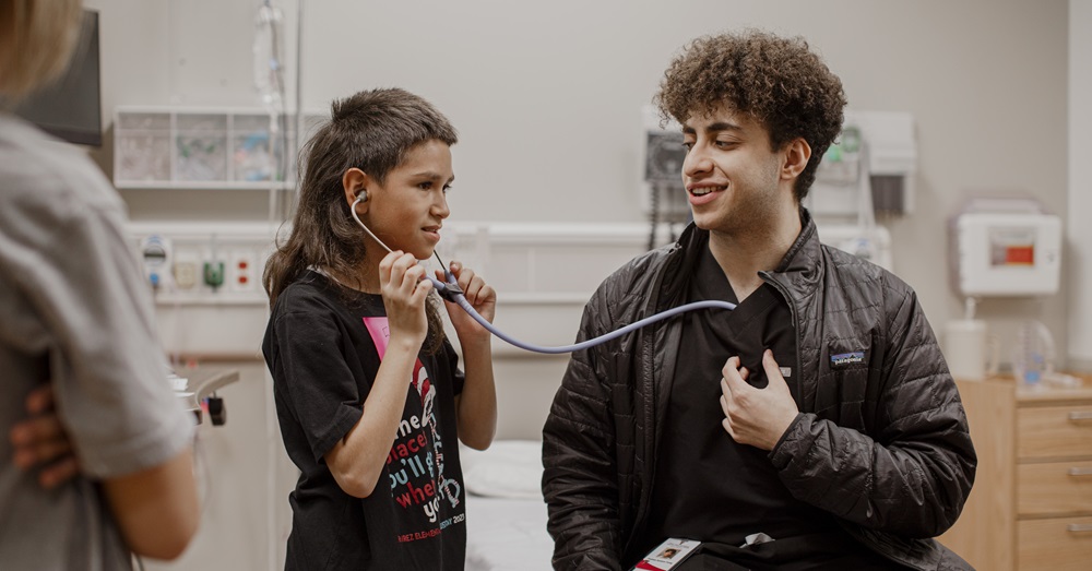 Elementary school student using a stethoscope during Docs for a Day mini camp