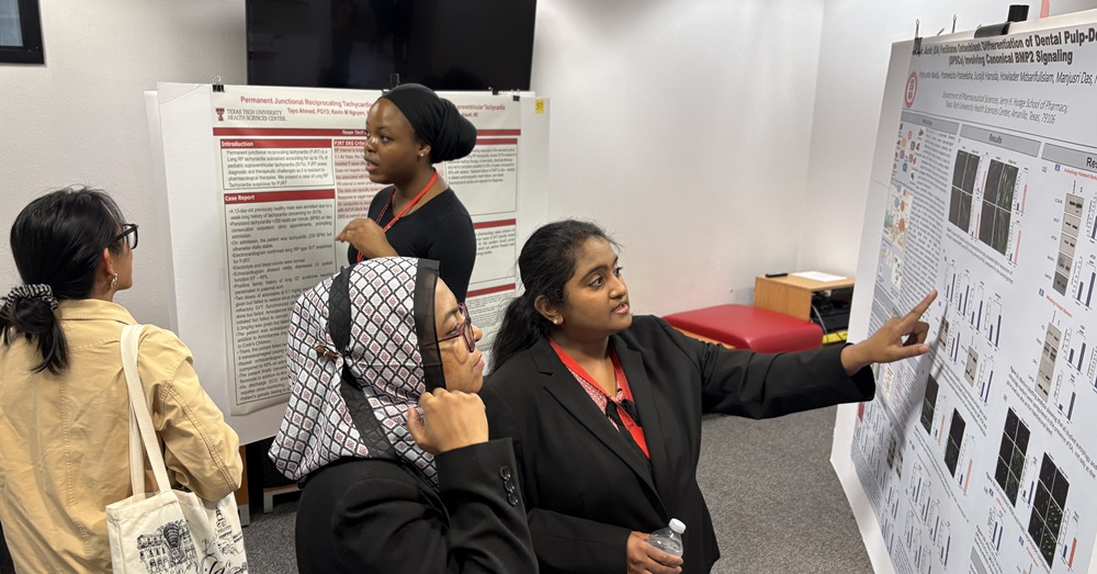 group of women discuss research presentations in front of posters