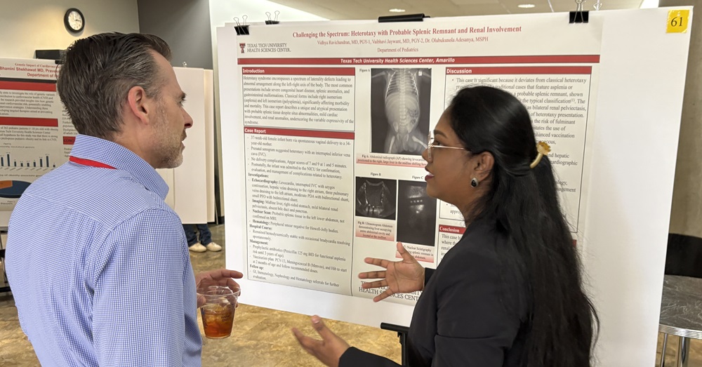 man and woman discuss poster presentation of research