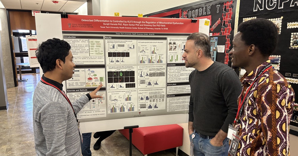 three men look at a research presentation poster