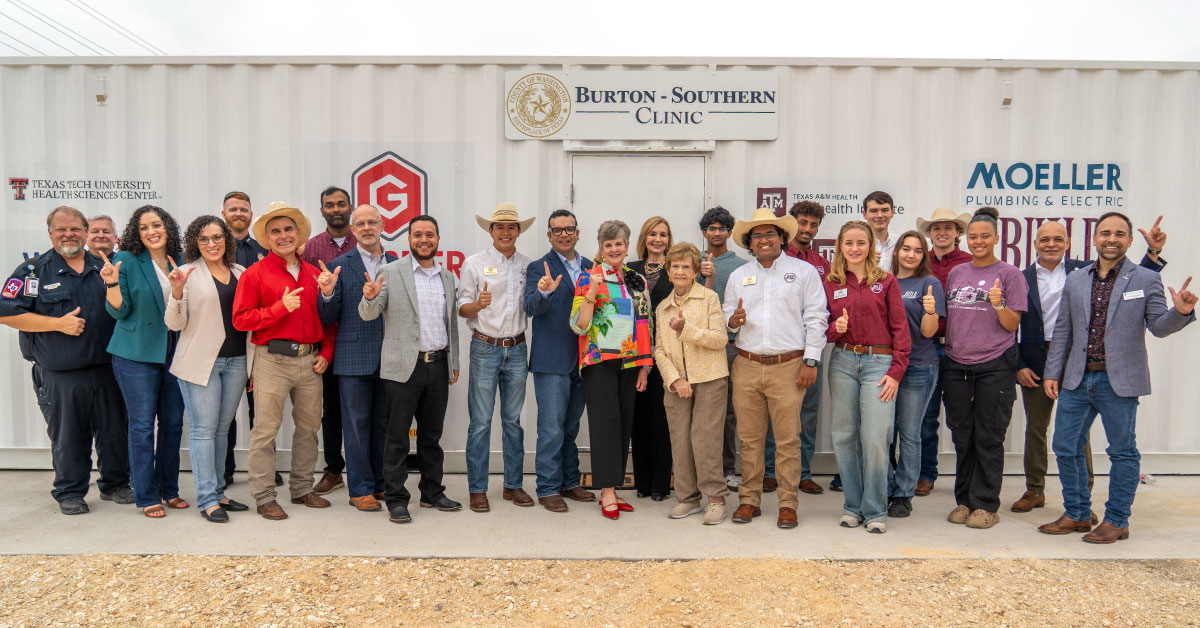 A large group of people stand in front of a converted shipping container.