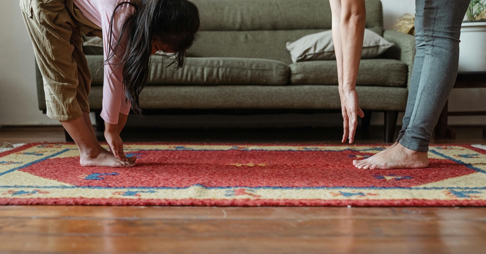 a child and woman stretching to touch their toes on a rug