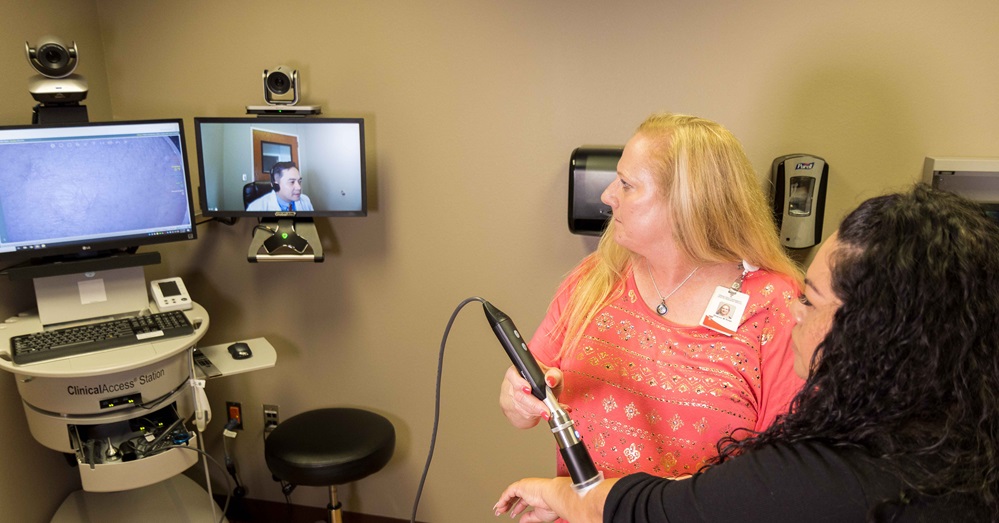 woman and health care professional use telehealth equipment