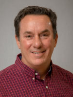 Man smiles for headshot.