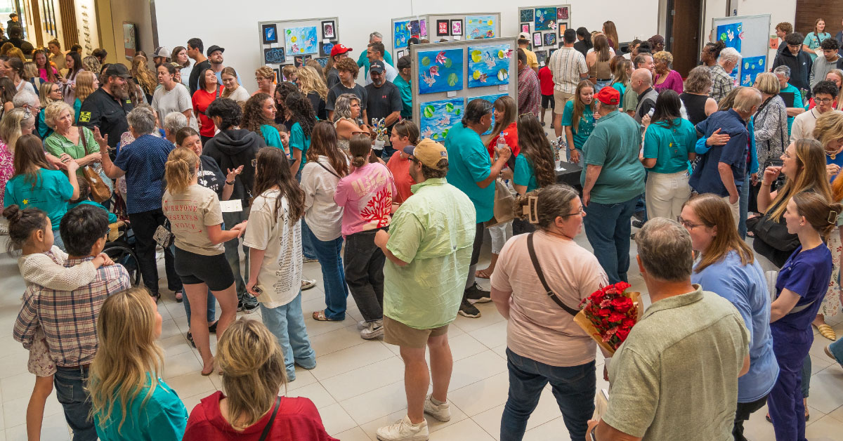 Large group of people look at art at an art show.