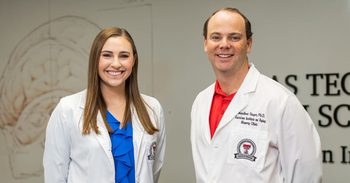 TWoman and man stand together wearing white coats.