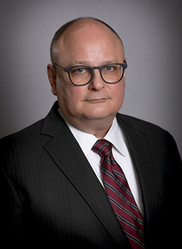 Man wears suit and tie for a headshot.