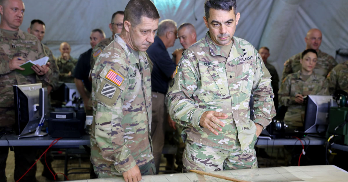 Two men in army uniforms look at a table.