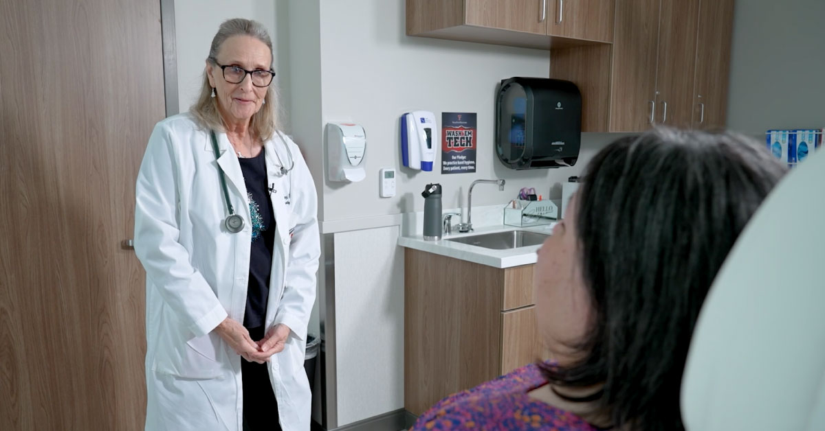 Woman physician talks to a woman patient in the exam room.